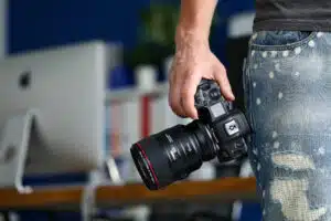 Male hand holding brand new mirrorless digital camera Canon r5 closeup